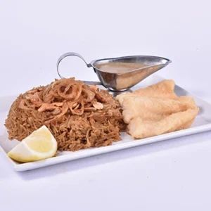 Angled view of a traditional vermicelli rice platter with golden fried chicken fingers, a silver gravy boat with tahini sauce, and lemon wedge, isolated on white.