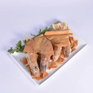Overhead flat-lay shot of an aesthetically arranged grilled fish platter, featuring fish steaks, golden crispy flatbread, lemon slices, and fresh greens on a white rectangular plate.