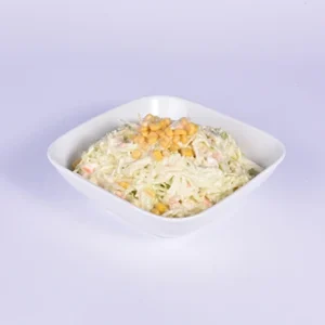 A fresh, creamy coleslaw salad served in a square white bowl, featuring shredded white cabbage, carrots, and yellow corn kernels on a clean white background.