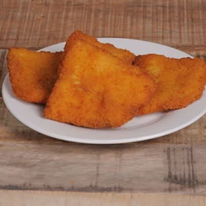 Overhead flat-lay view of two large golden crispy Wiener schnitzel cutlets served on a white round plate, set against a rustic wooden table background.