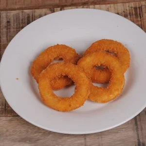 A white plate with several golden crispy fried onion rings, arranged on a rustic wooden table.
