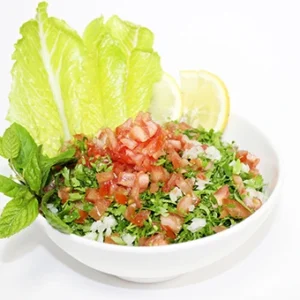 A fresh traditional Lebanese Tabbouleh salad in a white bowl, featuring finely chopped parsley, diced tomatoes, mint leaves, and lemon slices.