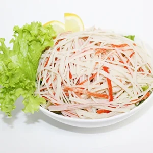 A bowl of authentic Kani salad featuring shredded imitation crab sticks, fresh lettuce, and a lemon wedge on a white background.