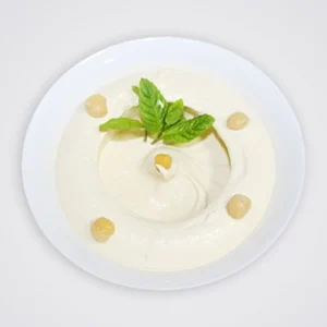 A white bowl filled with creamy hummus, topped with roasted chickpeas, a pool of olive oil, and fresh mint leaves on a white background.