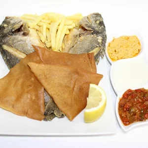 A white plate featuring a grilled fish, crispy flatbread, french fries, a lemon wedge, and three bowls of dipping sauces.