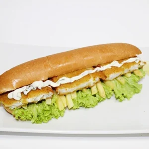 Crispy chicken sandwich with fresh lettuce, creamy garlic sauce, and lemon wedges on a white plate.