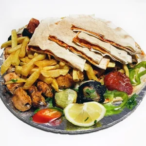Grilled chicken chunks platter with crispy french fries, mixed grilled vegetables, toast topped with tomato sauce, and lemon wedge on a foil tray.