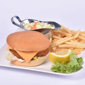 A crispy chicken burger with melted cheddar cheese in a soft bun, served with french fries, creamy coleslaw, and a lemon wedge on a white plate.