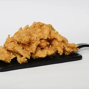 A black rectangular serving board covered with a large pile of golden, extra-crispy fried chicken tenders on a white background.