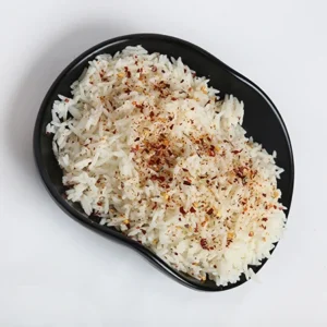 A black bowl filled with fluffy white rice topped with a generous sprinkling of red paprika and mixed spices, set against a plain white background.