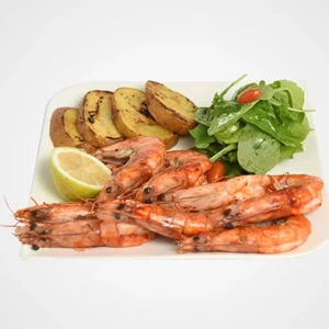A square white plate featuring a stack of char-grilled whole prawns in the front, roasted golden potato wedges on the left, a fresh green arugula salad with cherry tomatoes on the right, and a lime wedge in the middle.